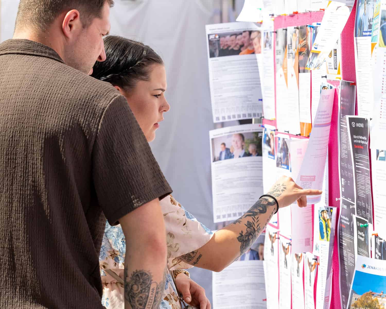 Zwei Besucher lesen Jobangebote an der Jobwall